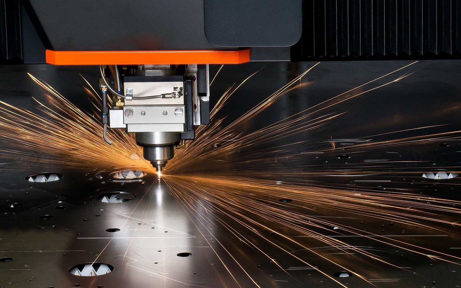 high-power-fiber-laser-applications Máquina de corte a laser CNC realizando perfuração em chapa metálica com emissão de faíscas.